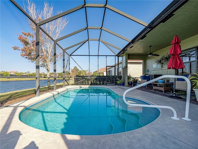 outdoor pool with a ceiling fan, a patio area, glass enclosure, and a water view