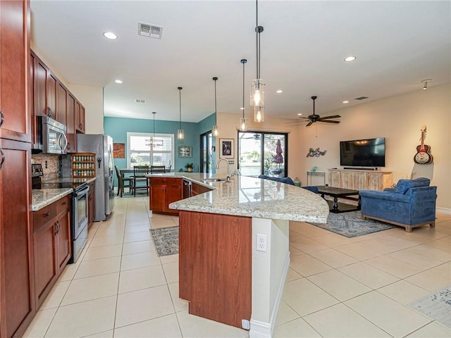 kitchen featuring light stone counters, stainless steel appliances, a sink, visible vents, and hanging light fixtures