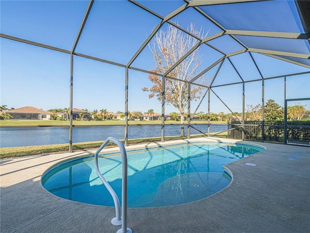 outdoor pool with a water view, glass enclosure, and a patio