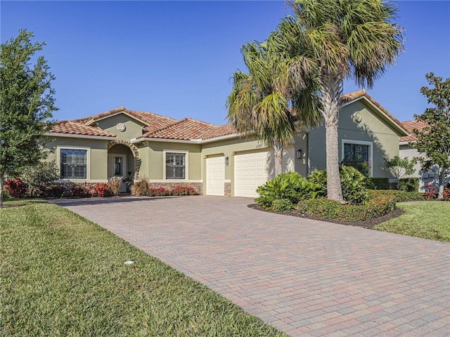 mediterranean / spanish home featuring a garage and a front lawn