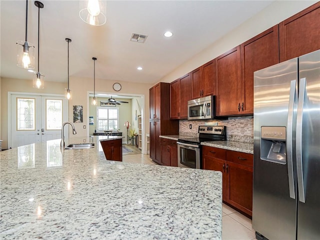 kitchen with light stone counters, a sink, french doors, appliances with stainless steel finishes, and backsplash