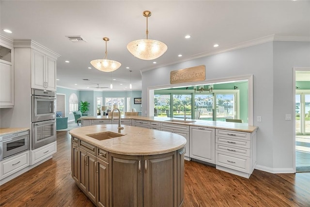 kitchen featuring white cabinetry, stainless steel appliances, sink, and a center island with sink