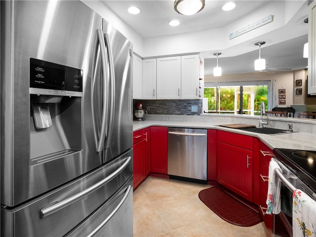 kitchen featuring light tile patterned flooring, stainless steel appliances, hanging light fixtures, sink, and white cabinets