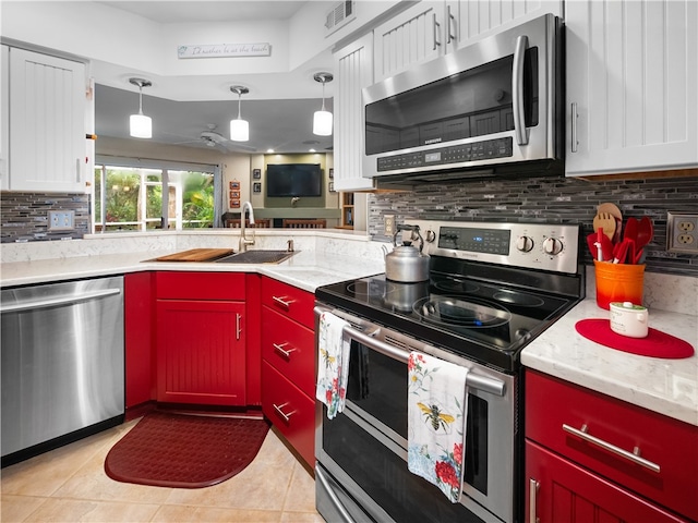 kitchen with stainless steel appliances, white cabinets, hanging light fixtures, sink, and light tile patterned floors