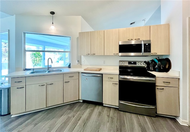 kitchen featuring pendant lighting, light brown cabinets, sink, wood-type flooring, and stainless steel appliances