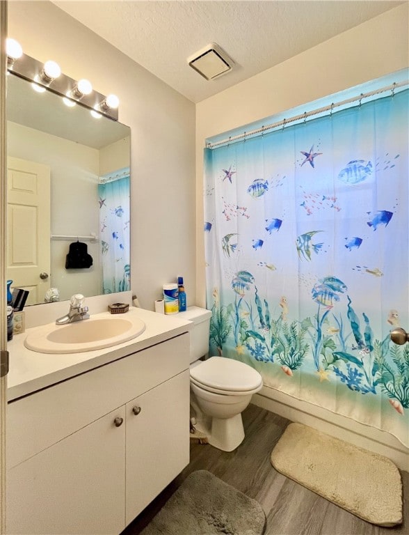 full bathroom with shower / tub combo, vanity, a textured ceiling, hardwood / wood-style flooring, and toilet