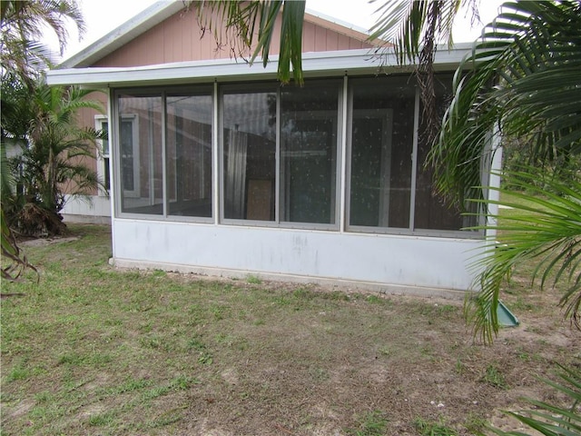 back of property featuring a lawn and a sunroom