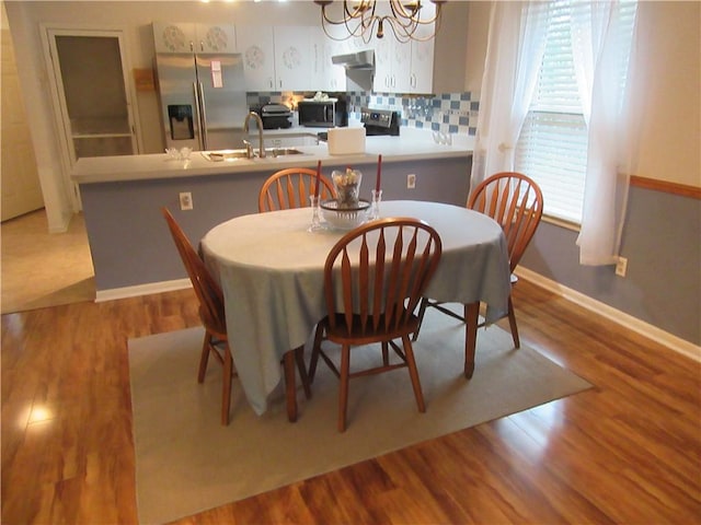 dining space featuring a notable chandelier, wood finished floors, and baseboards