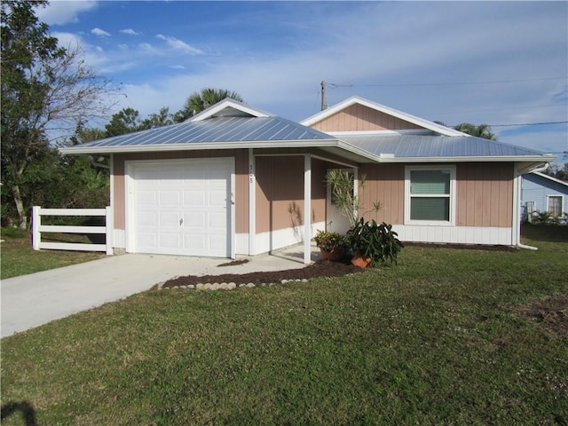 view of front of home with a front lawn, fence, metal roof, a garage, and driveway