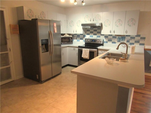 308 14th Pl SW, Vero Beach, FL 32962 - kitchen with stainless steel appliances, exhaust hood, a peninsula, light countertops, and decorative backsplash