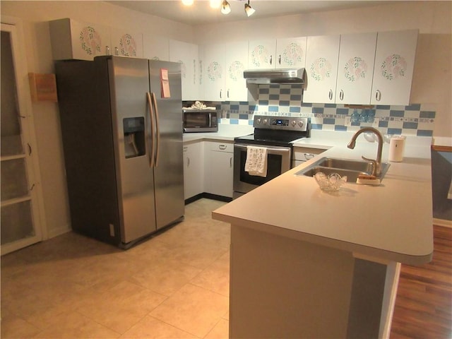 kitchen with under cabinet range hood, decorative backsplash, appliances with stainless steel finishes, a peninsula, and a sink