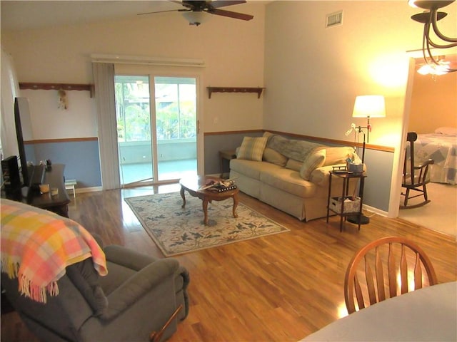 living area featuring baseboards, wood finished floors, visible vents, and ceiling fan