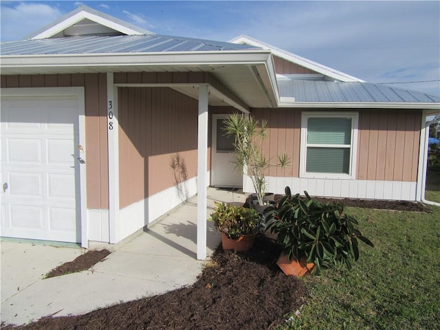 doorway to property with an attached garage and metal roof