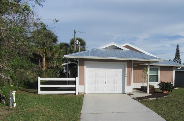 ranch-style house featuring an attached garage, driveway, metal roof, and a front lawn