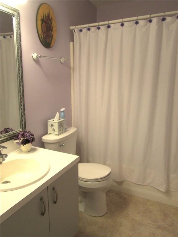 bathroom featuring vanity, tile patterned floors, toilet, and shower / bath combo with shower curtain