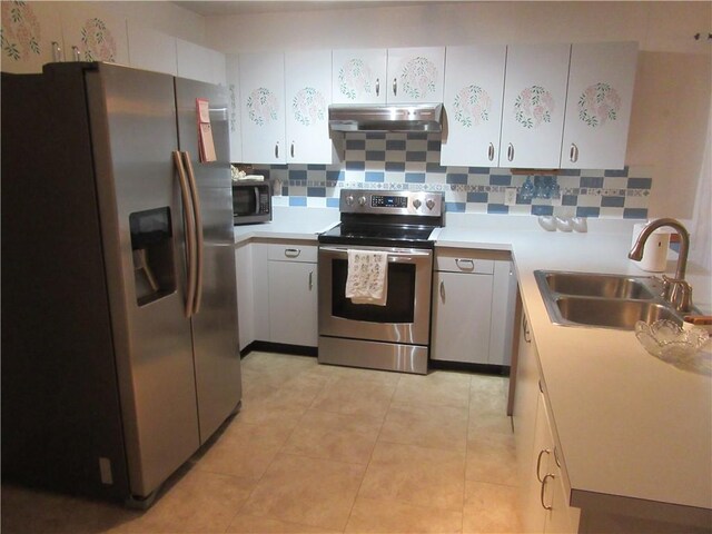 kitchen with under cabinet range hood, light countertops, decorative backsplash, appliances with stainless steel finishes, and a sink