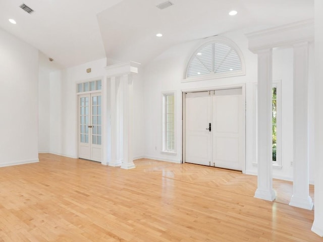 foyer with a wealth of natural light, visible vents, decorative columns, and light wood finished floors