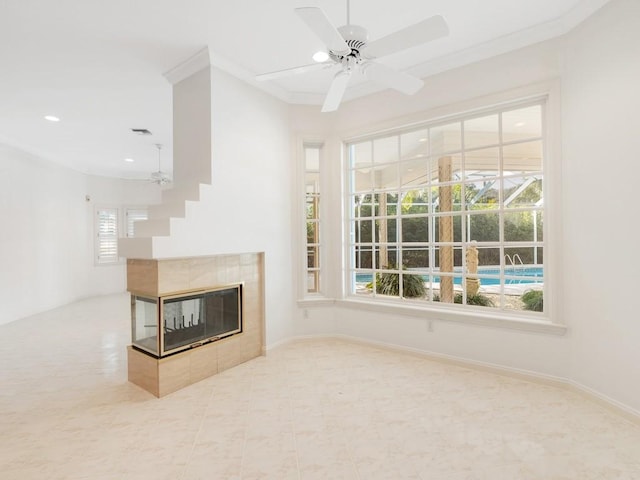 unfurnished living room with crown molding, a fireplace, visible vents, ceiling fan, and baseboards