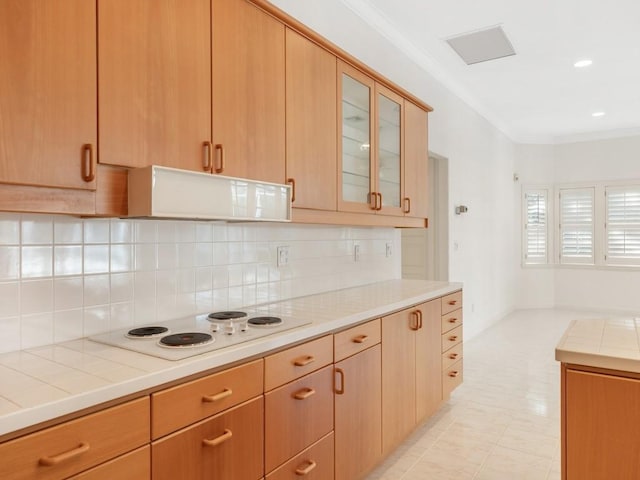 kitchen featuring tasteful backsplash, ornamental molding, extractor fan, tile counters, and white electric stovetop