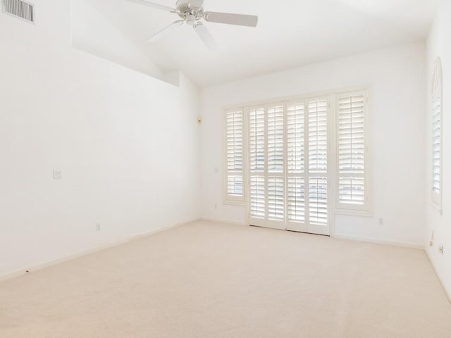 carpeted spare room featuring a ceiling fan, lofted ceiling, visible vents, and baseboards