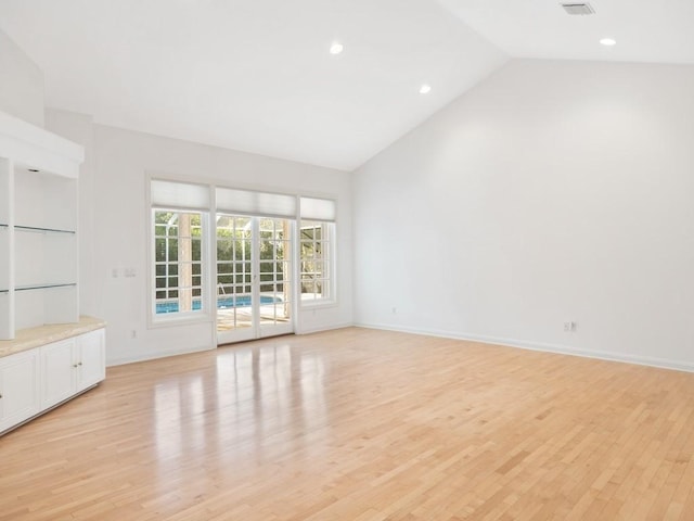 unfurnished living room with light hardwood / wood-style floors and high vaulted ceiling