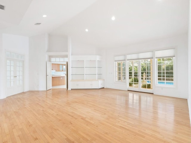 unfurnished living room featuring high vaulted ceiling and light wood-type flooring