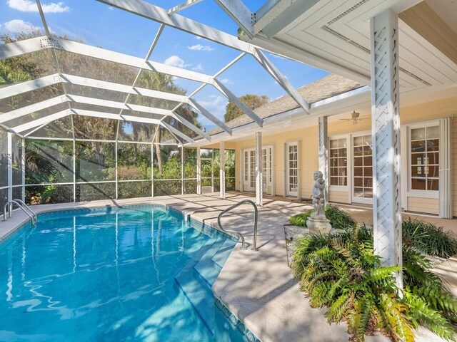 view of swimming pool with glass enclosure, ceiling fan, french doors, and a patio