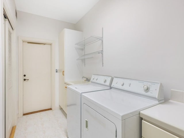 laundry area featuring light floors, a sink, and independent washer and dryer