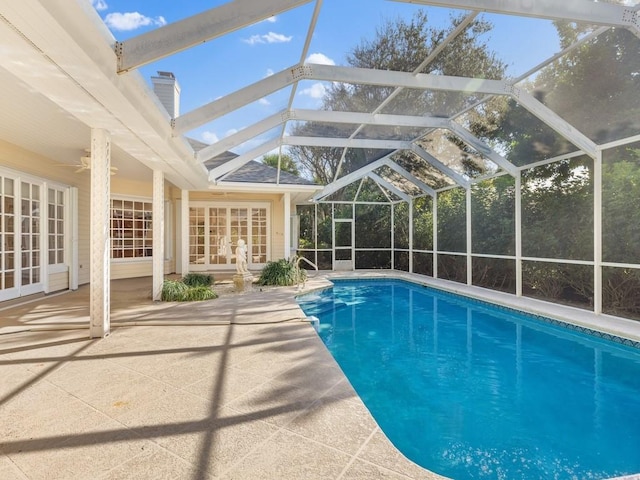 outdoor pool featuring glass enclosure, a ceiling fan, a patio, and french doors