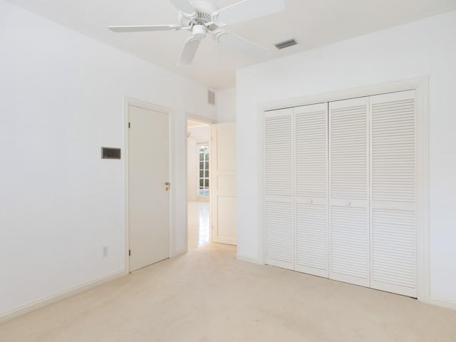 unfurnished bedroom featuring a closet, light colored carpet, and ceiling fan