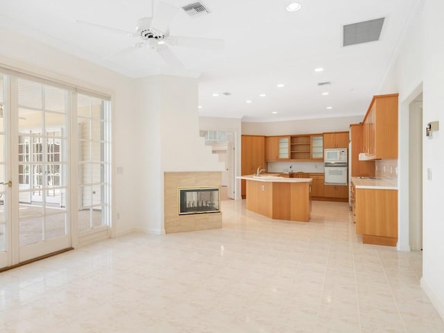 kitchen with white appliances, a center island with sink, visible vents, and light countertops