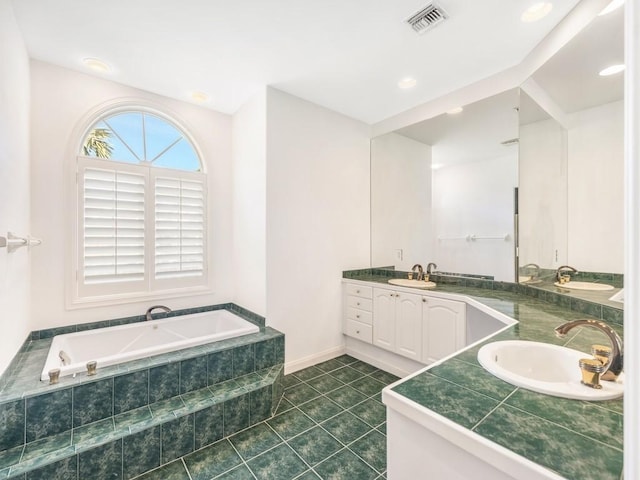 bathroom featuring vanity, a relaxing tiled tub, and tile patterned floors