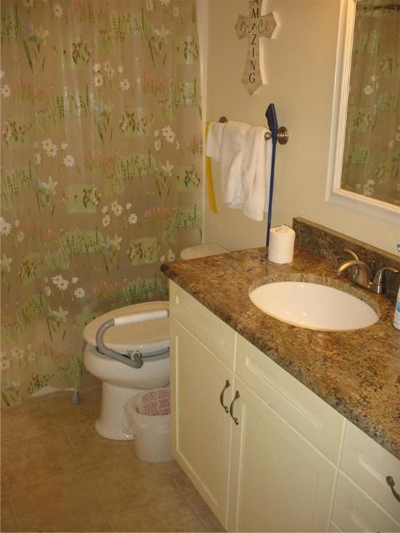 bathroom with toilet, vanity, and tile patterned floors