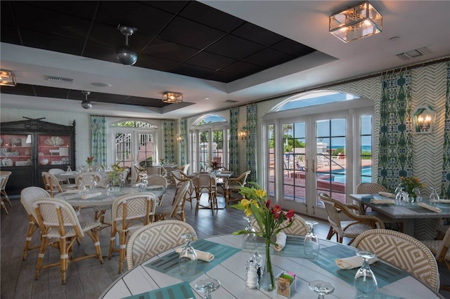 dining room with a raised ceiling and french doors