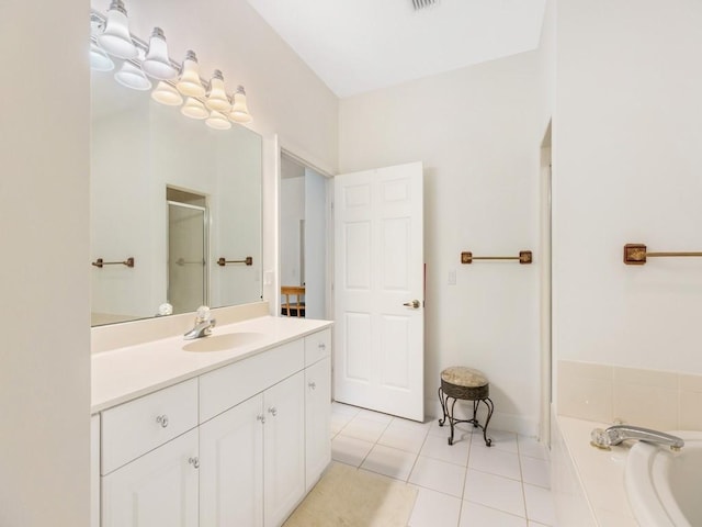 bathroom featuring tile patterned flooring, a relaxing tiled tub, and vanity