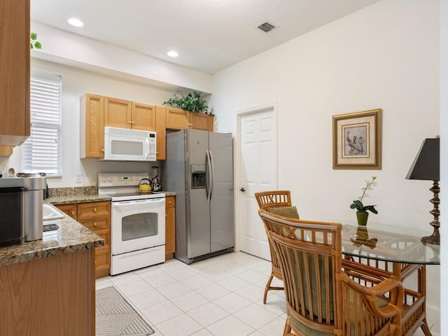 kitchen with stone countertops, white appliances, and light tile patterned floors