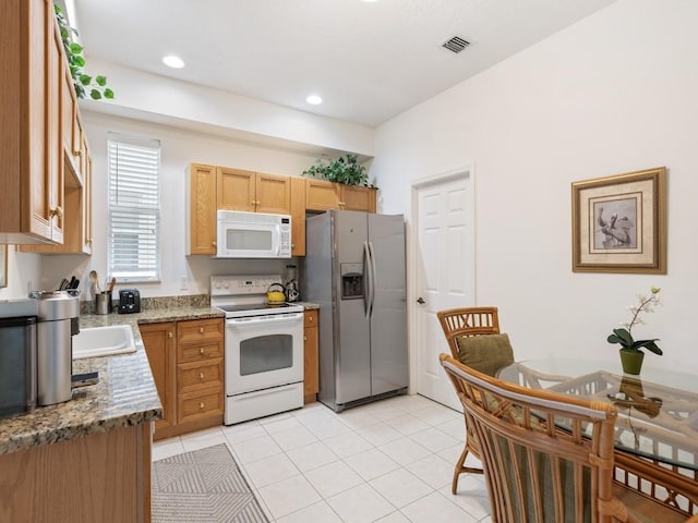 kitchen with light stone counters, white appliances, and light tile patterned floors