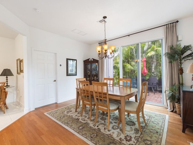 dining room featuring light wood-type flooring and an inviting chandelier