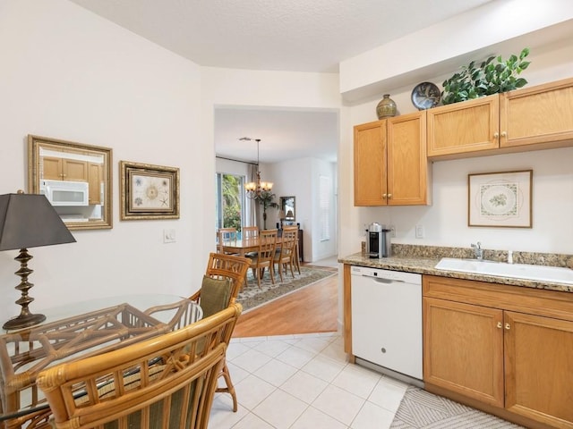 kitchen with white appliances, sink, decorative light fixtures, a notable chandelier, and light stone counters