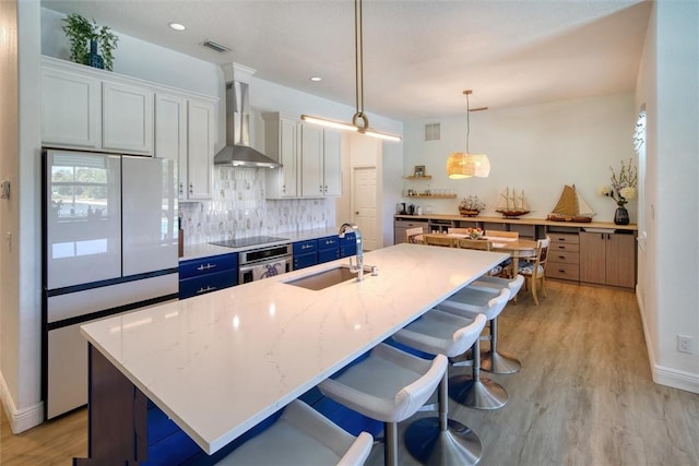 3612 2nd St SW, Vero Beach, FL 32968 - kitchen with wall chimney exhaust hood, oven, freestanding refrigerator, black electric stovetop, and backsplash