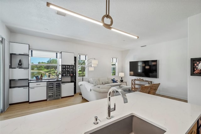 3612 2nd St SW, Vero Beach, FL 32968 - living area with wine cooler, healthy amount of natural light, light wood-style flooring, and a textured ceiling