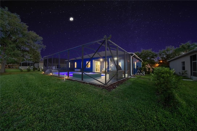 3612 2nd St SW, Vero Beach, FL 32968 - back of house at night with a lawn, an outdoor pool, glass enclosure, and a patio area