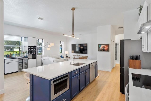 3612 2nd St SW, Vero Beach, FL 32968 - kitchen featuring blue cabinetry, beverage cooler, stainless steel dishwasher, light wood finished floors, and light countertops