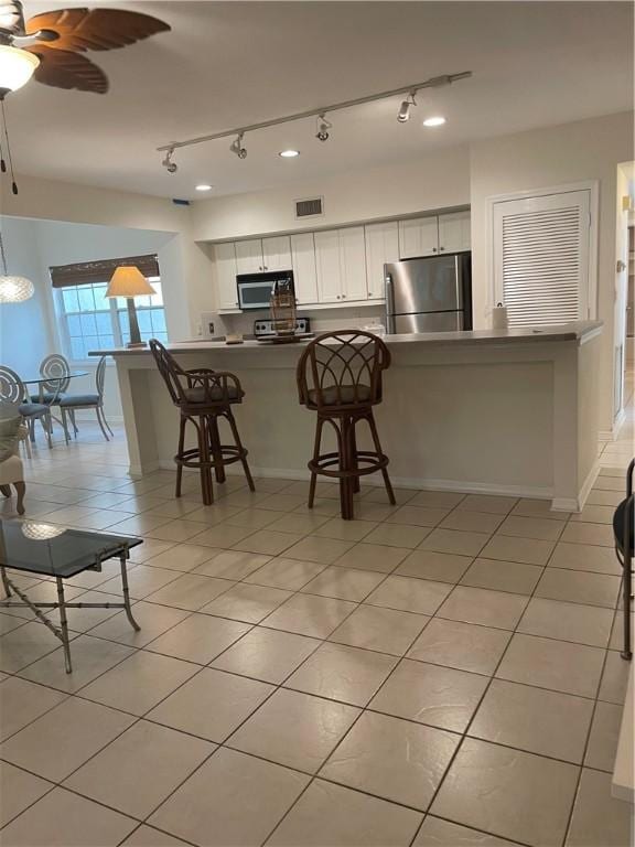 1275 Winding Oaks Cir E Unit 702, Vero Beach, FL 32963 - kitchen featuring appliances with stainless steel finishes, light tile patterned floors, white cabinets, a breakfast bar area, and a peninsula