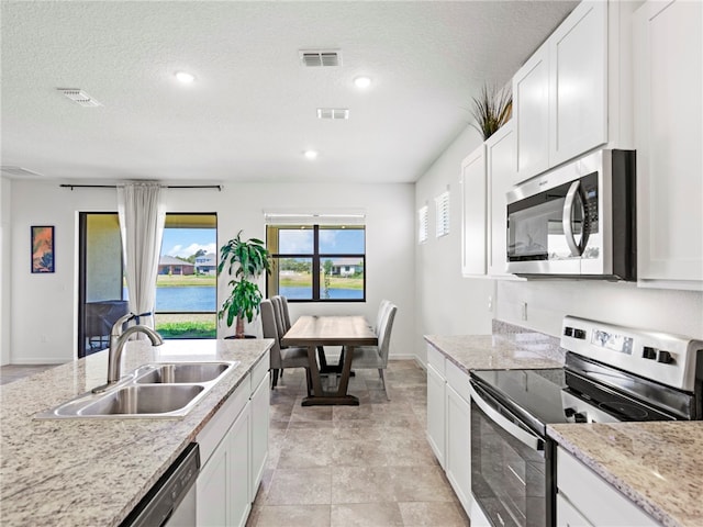 kitchen featuring white cabinetry, sink, light stone counters, a textured ceiling, and appliances with stainless steel finishes