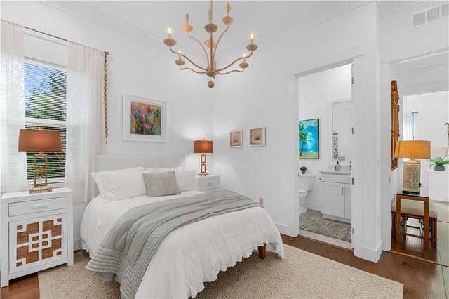 202 Strand Sq, Vero Beach, FL 32963 - bedroom with wood finished floors, a chandelier, ensuite bath, and baseboards