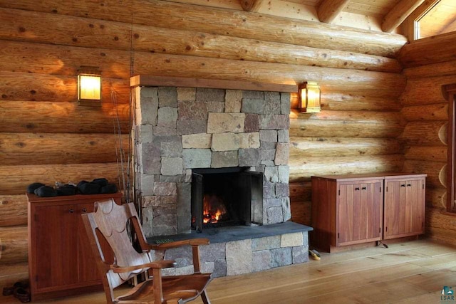 unfurnished living room with a fireplace, rustic walls, light hardwood / wood-style floors, and beamed ceiling