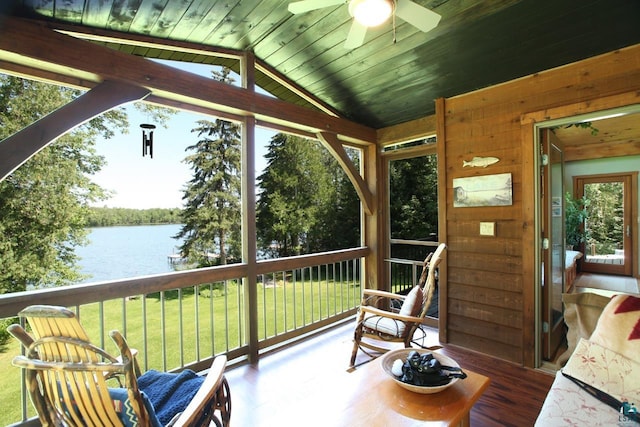 sunroom featuring ceiling fan, vaulted ceiling, and a water view