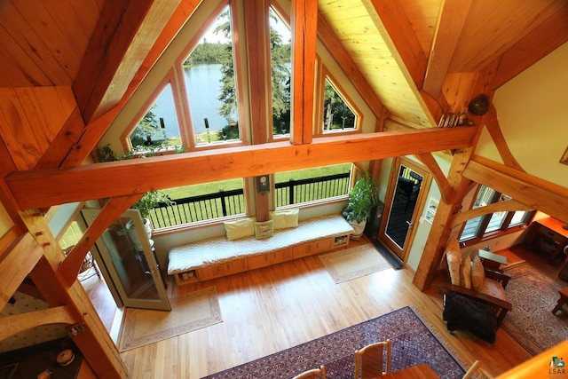 living room featuring lofted ceiling with beams, hardwood / wood-style floors, a water view, and wood ceiling