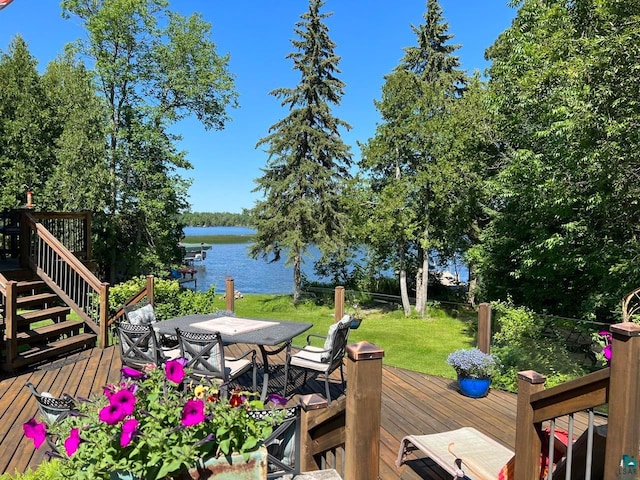 wooden terrace with a water view and a yard